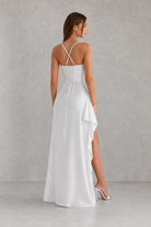 Woman wearing a white dress with thin straps on a gray background