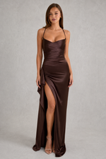 Woman wearing a brown evening gown with a slit on a gray background