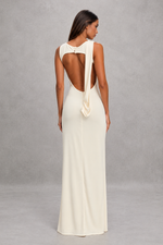 Woman wearing a white evening gown with a bow detail on a gray background