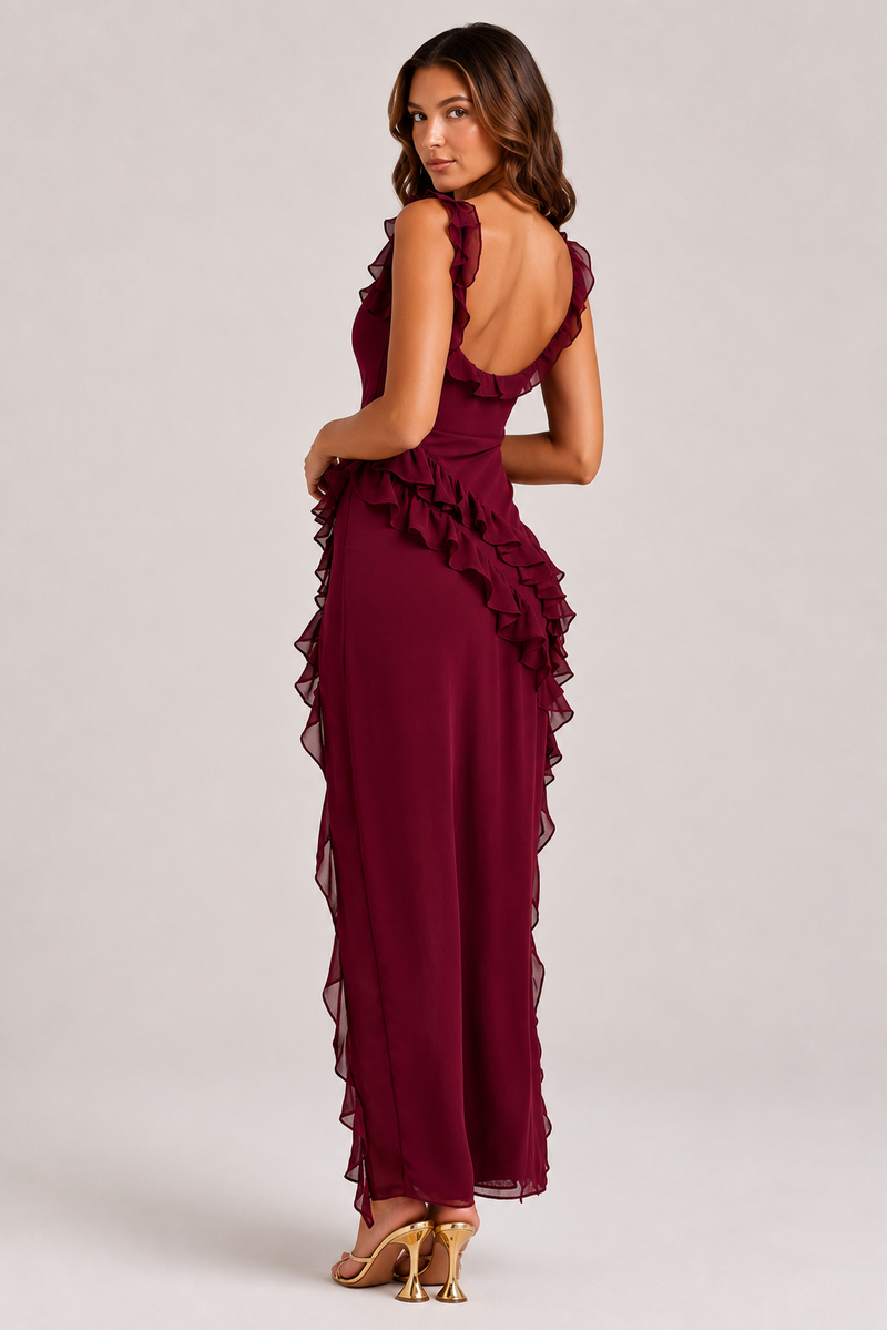 Woman wearing a burgundy evening gown with ruffled details on a white background