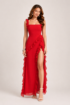 Woman wearing a red evening gown with ruffles on a plain background