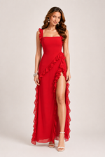 Woman wearing a red evening gown with ruffles on a plain background