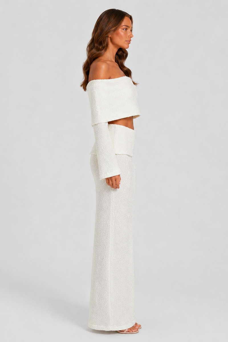 Woman wearing a white off-shoulder top and skirt set against a plain background