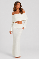 Woman wearing a white off-shoulder top and skirt set against a plain background