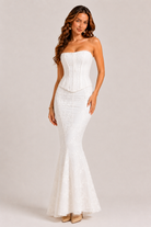 Woman wearing a white strapless gown on a plain background