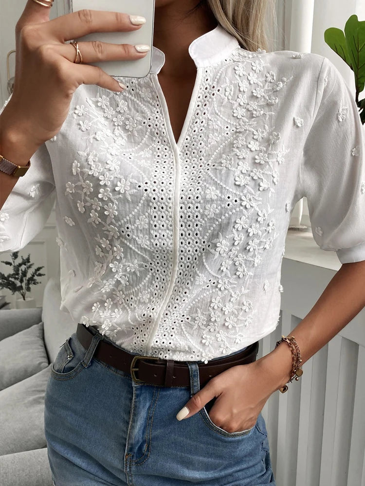 Person wearing a white blouse with lace details and blue jeans indoors.