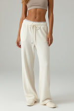 Person wearing white ribbed lounge pants on a wooden floor.