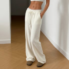 Person wearing white lounge pants standing on a wooden floor.