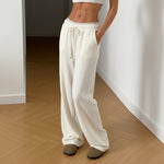Person wearing white lounge pants standing on a wooden floor.