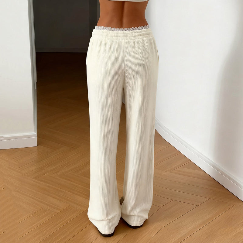 Person wearing white wide-leg pants on a wooden floor.