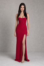 Woman wearing a red evening gown with a high slit on a gray background