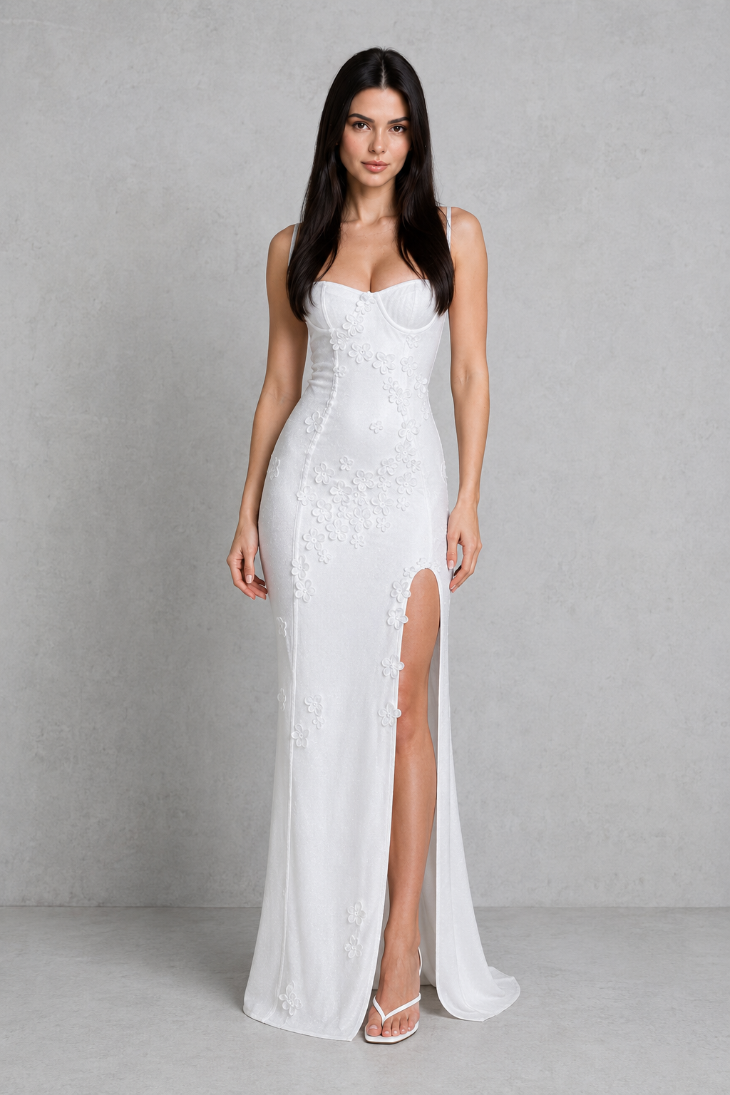 Woman wearing a white strapless gown with a high slit on a gray background