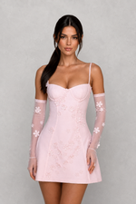 Woman wearing a pink lace dress with sheer sleeves against a gray background