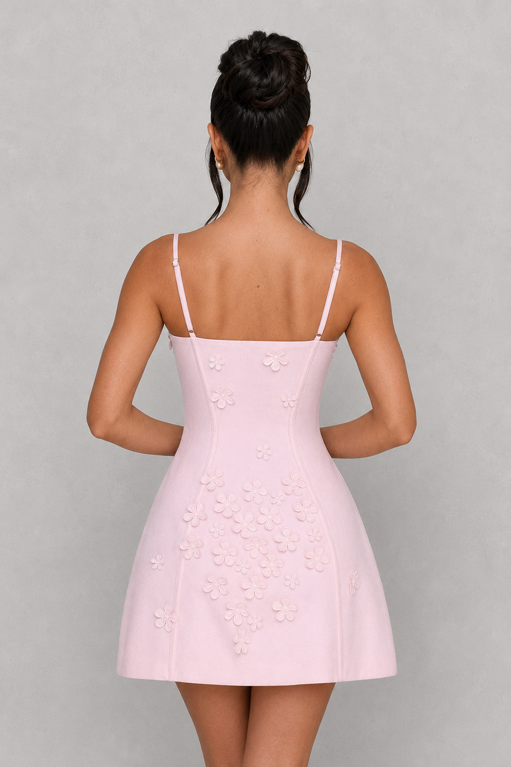 Woman wearing a light pink dress with thin straps on a gray background