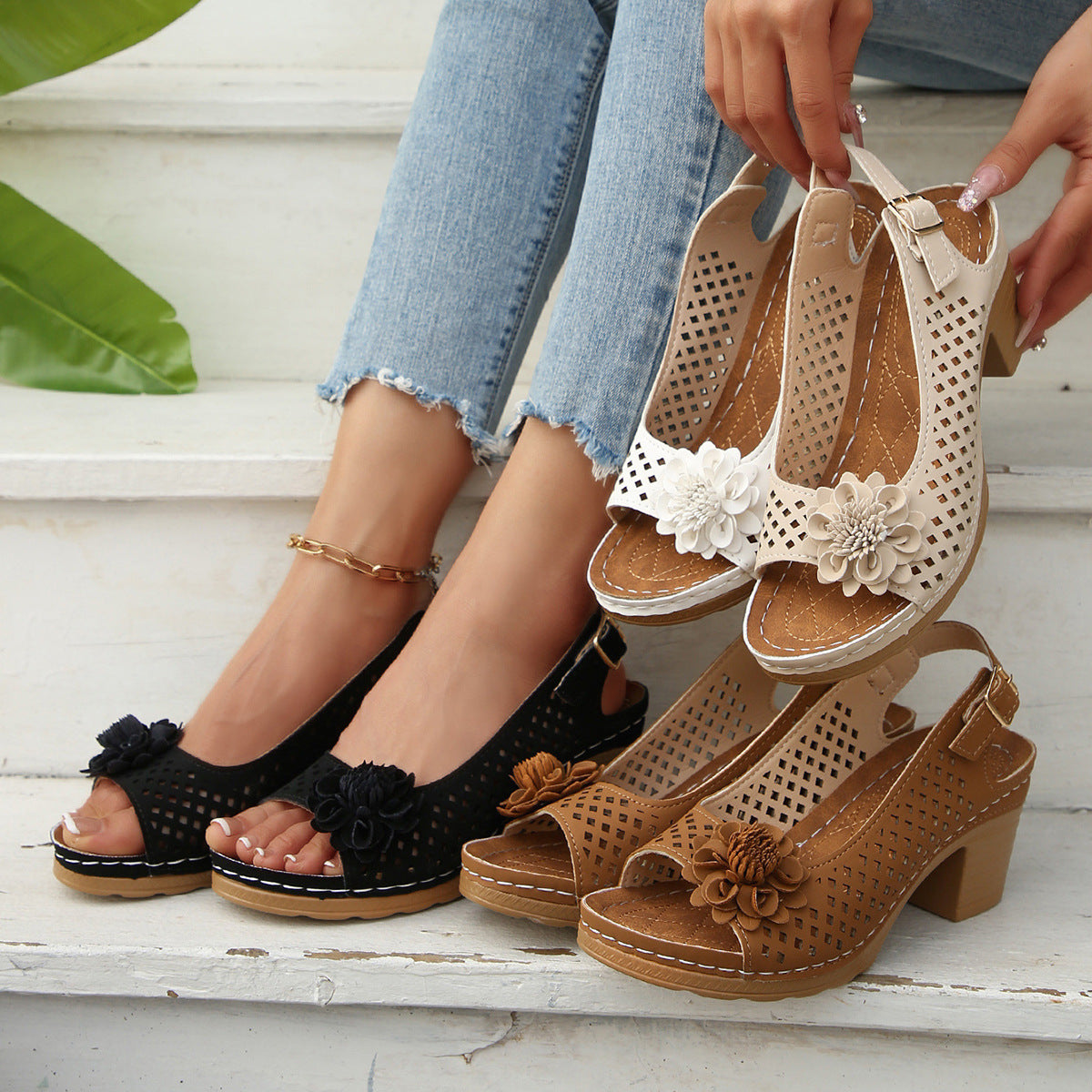 Pair of black and brown open-toe shoes with floral details on a white surface.