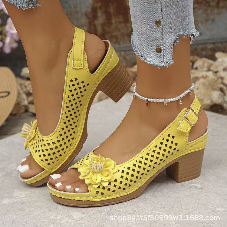 Yellow open-toe shoes with floral details worn by a person.