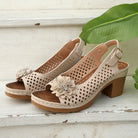 Beige open-toe shoes with floral details on a wooden surface