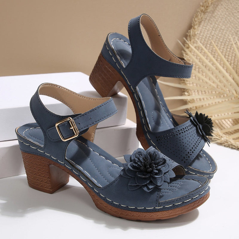 Blue sandals with wooden block heels and floral decorations on a neutral background