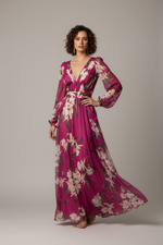 Woman in a pink floral dress standing in a garden setting