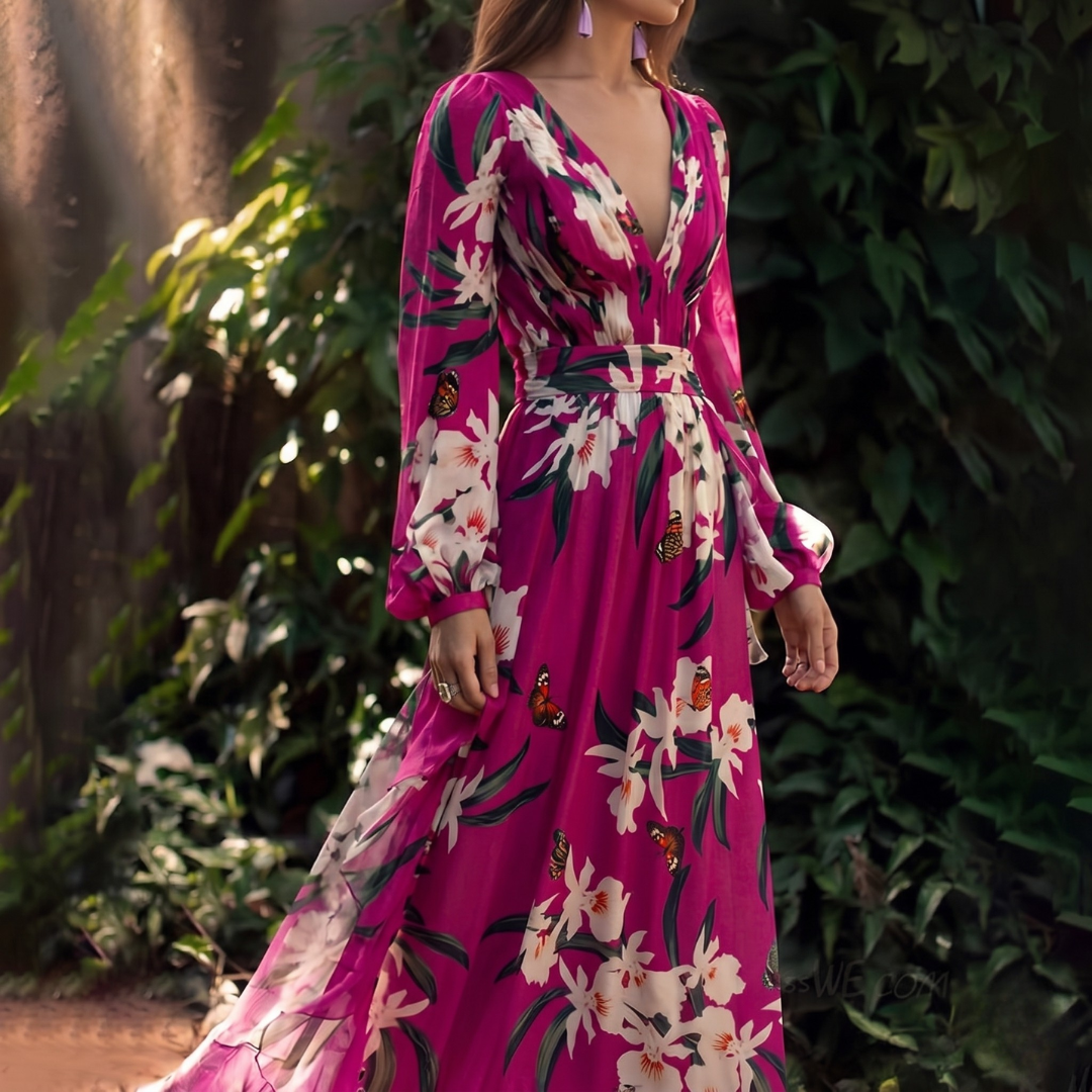 Woman wearing a vibrant pink dress with floral and butterfly patterns in a natural setting.