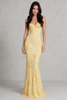 Woman wearing a yellow evening gown against a gray background