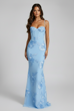 Woman wearing a light blue lace evening gown against a gray background