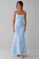 Woman wearing a light blue lace dress against a gray background