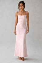 Woman wearing a light pink dress against a gray background