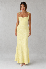Woman wearing a light yellow evening gown against a gray background