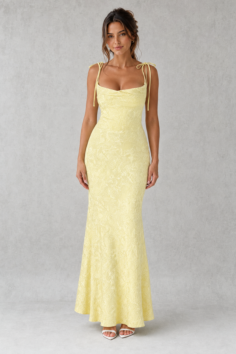 Woman wearing a light yellow evening gown against a gray background