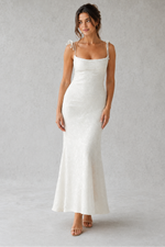 Woman wearing a white slip dress against a plain background