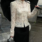 Person wearing a lace blouse and holding an umbrella on a wet pavement.