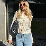 Woman wearing a lace top and jeans, holding a Chanel bag outdoors.
