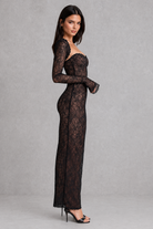 Woman wearing a black lace dress against a gray background
