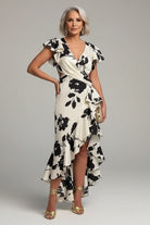 Woman in a black and white floral dress standing by a poolside.