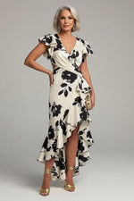 Woman in a black and white floral dress standing by a poolside.