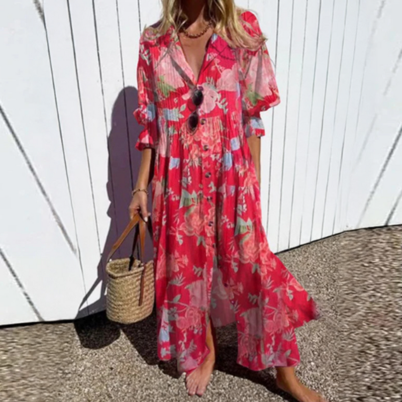 Woman wearing a red floral dress against a white wall.