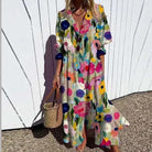 Woman wearing a colorful floral dress holding a straw bag against a white wall.