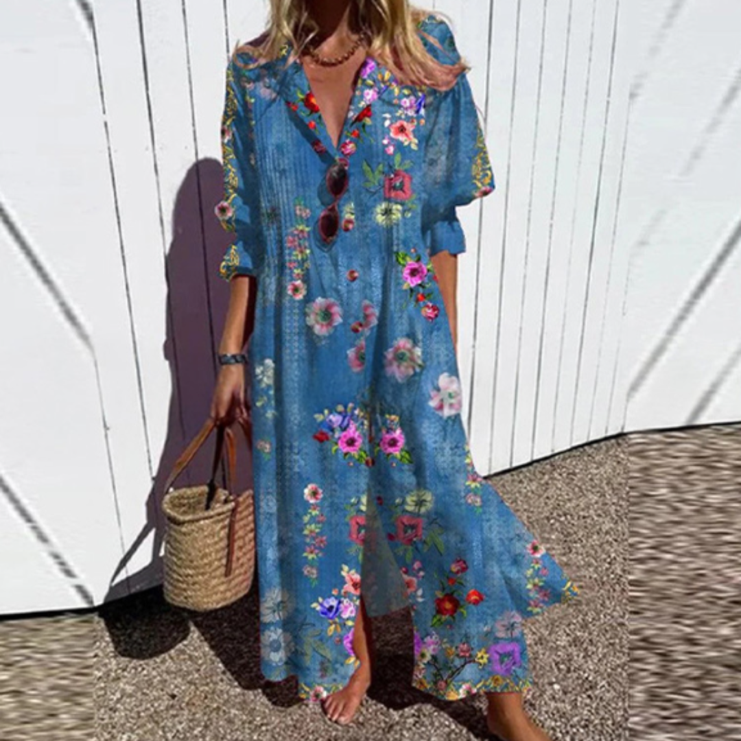 Woman wearing a blue floral dress holding a straw bag against a white wall.