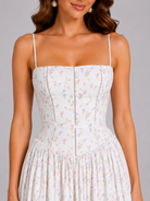Woman wearing a floral dress with thin straps on a gray background