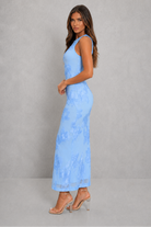 Woman wearing a light blue lace dress against a gray background