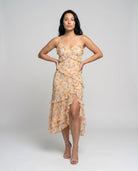 Woman wearing a floral dress with a high slit on a plain background