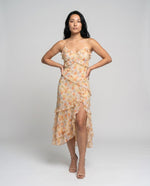 Woman wearing a floral dress with a high slit on a plain background