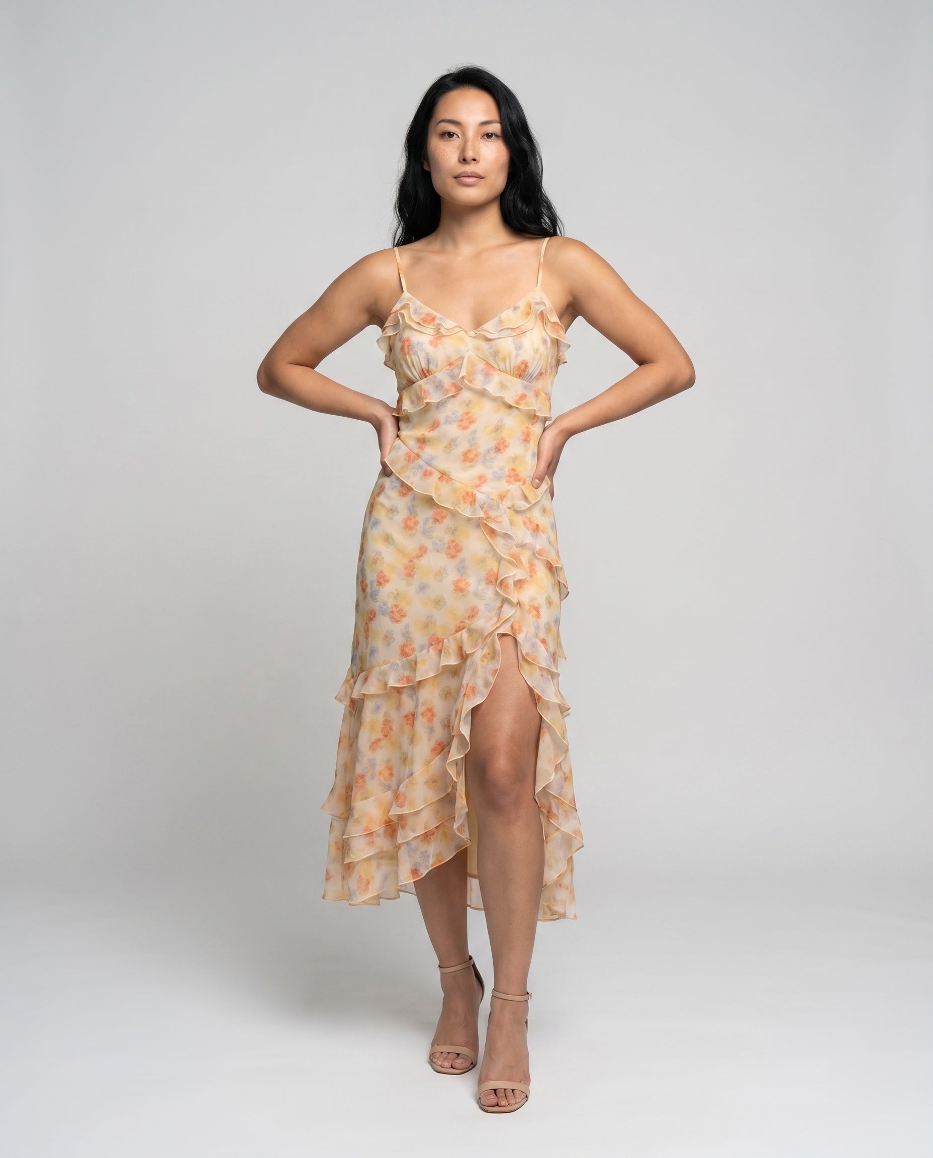 Woman wearing a floral dress with a high slit on a plain background