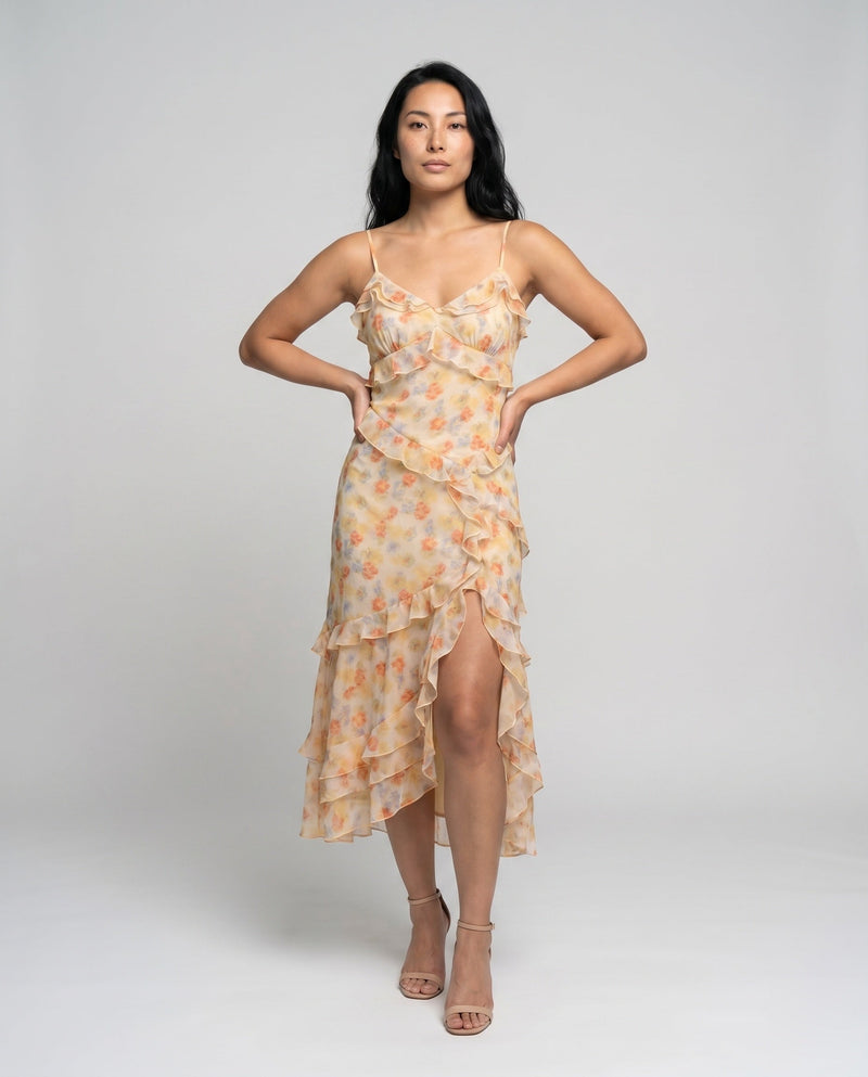 Woman wearing a floral dress with a high slit on a plain background