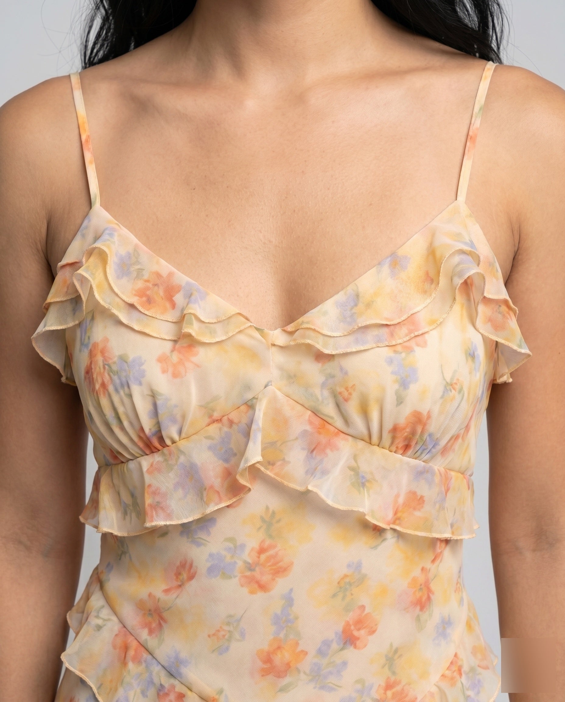 Floral ruffled top worn by a person on a plain background
