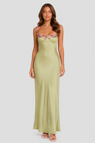 Woman wearing a green strapless dress with floral embroidery on a white background