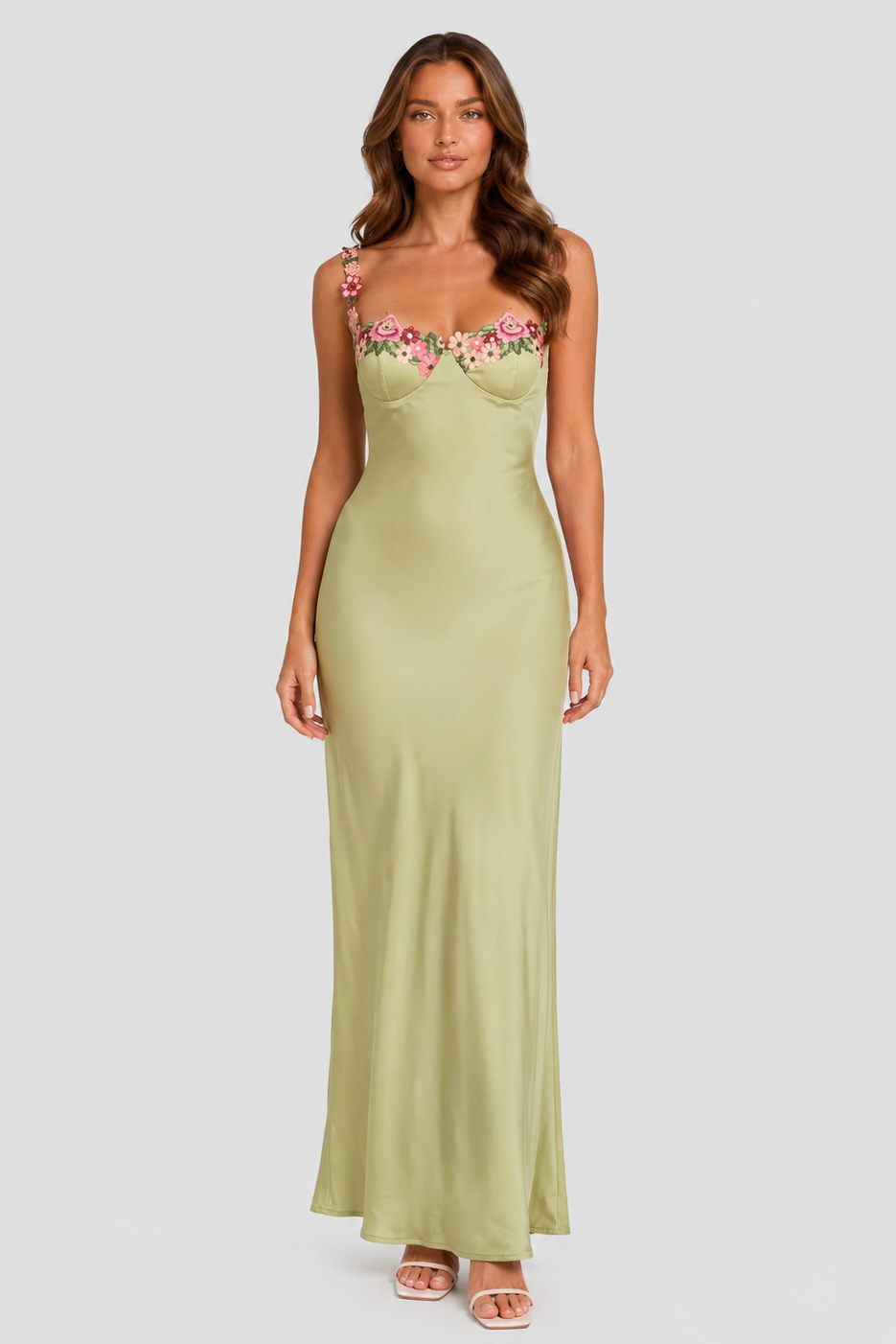 Woman wearing a green strapless dress with floral embroidery on a white background