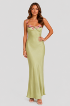 Woman wearing a green strapless dress with floral embroidery on a white background
