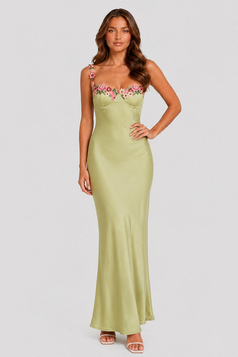Woman wearing a green strapless dress with floral embroidery on a white background